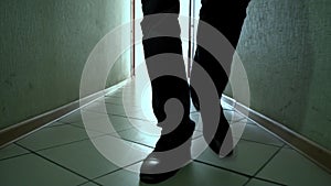 Man in shoes walks down a dirty corridor forward on camera, close-up