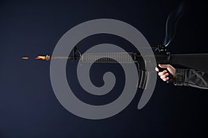 Man shooting from assault rifle on dark background, closeup