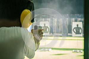 Man shooting automatic pistol to target in shooting range