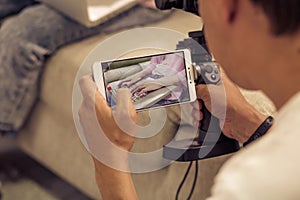 Man shooting girl typing on laptop with cell phone camera.