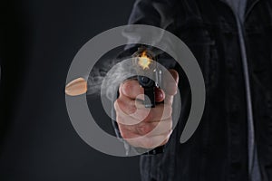 Man shooting from gun on black background, closeup