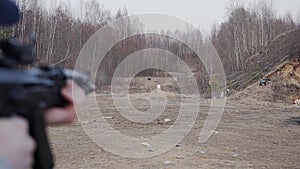 A man shoots at a target with an assault rifle at the shooting range.