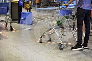 Man, with a shopping cart, doing groceries in a supermarket during coronavirus covid-19 pandemic