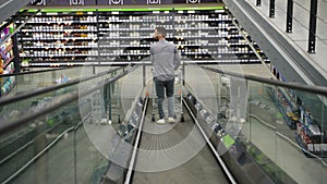 A man with shopping cart on escalator in a hardware store