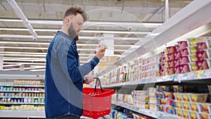 man is shopping in grocery in supermarket, choosing low calorie yogurt