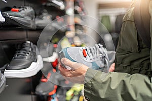 Man Shopping for Sneakers in Store, holding pair of shoes in hands photo