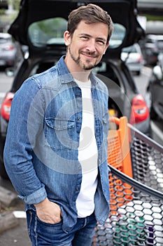 man with shopping trolley in supermarket carpark