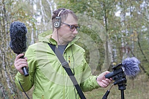 The man with Shotgun Condenser Microphone and headphones is recording the sounds of nature.