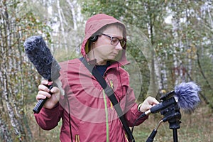 The man with Shotgun Condenser Microphone and headphones is recording the sounds of nature.