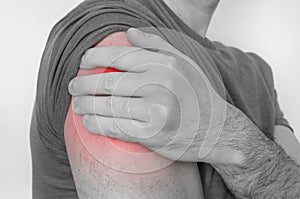 Man with shoulder pain is holding his aching arm