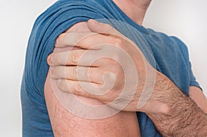 Man with shoulder pain is holding his aching arm