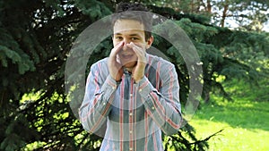 Man Shouting Into the Distance Outdoors in a Lush Green Park During Daytime