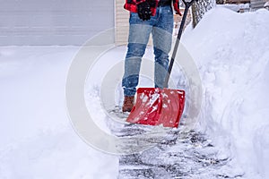 Man shoveling deep snow by hand with a red shovel