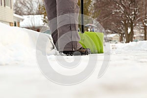 Man shoveling and removing snow in front of his house in the suburb.