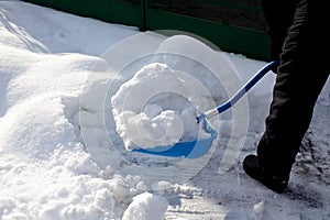 Man shoveling  snow big blue shovel in the suburb