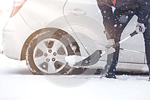 Man shoveling snow to free his stuck car.