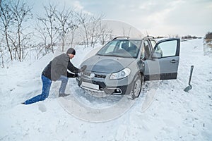 Man shoveling snow to free his stuck car photo