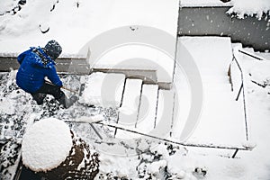 Man shovelling staircases with a snow shovel or pusher, topview photo