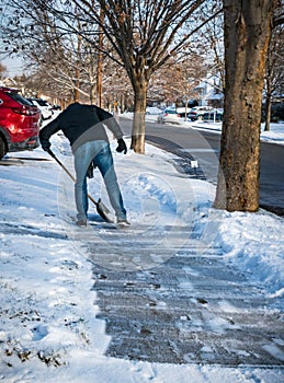 Man shovels snow from sidewalk by house