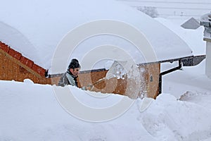 A man shovels snow from a sidewalk in the winter