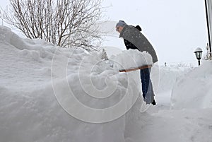 A man shovels snow from a sidewalk in the winter