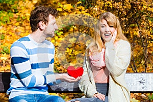 Man show feelings to girl in autumnal park.