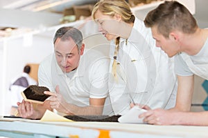man showing brush to painter apprentices