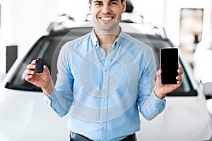 Man showing car key and smartphone in dealership center