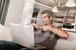 Man showing gesture in sign language, using laptop