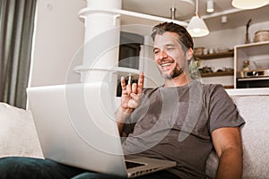 Man showing gesture in sign language, using laptop
