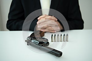 Man showing a gun and ammunition on table.