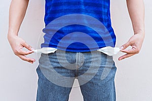 Man showing his empty pocket on wall background