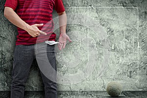 Man showing his empty pockets with football field on concrete wall