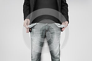 Man showing his empty pockets on gray wall