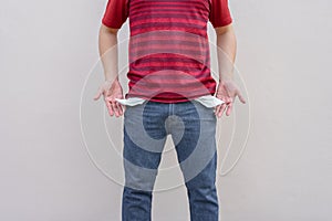 Man showing his empty pockets on wall background