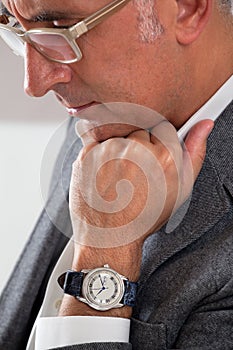 Man showing his watch while thinking with hand on chin