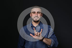 Man showing I LOVE YOU gesture in sign language on black