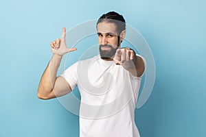 Man showing looser gesture and pointing at camera, looking with grumpy face.