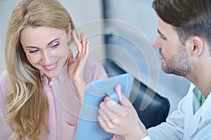 Man showing mirror and woman trying on hearing aid