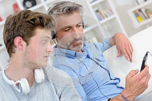 Man showing mp3 screen to son who looks uninterested