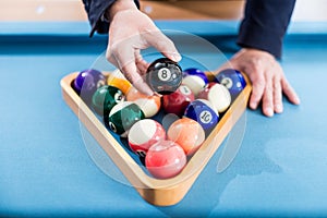 Man showing number eight black pool ball on billiards table