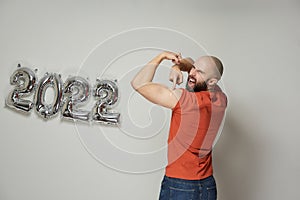 A man is showing a plaster on his shoulder after vaccination near balloons