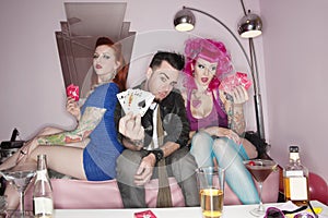 Man showing playing cards tattooed women sitting besides