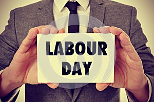 Man showing a signboard with the text labour day, filtered