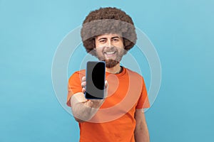 Man showing smart phone with blank black screen, presenting area for advertisement.