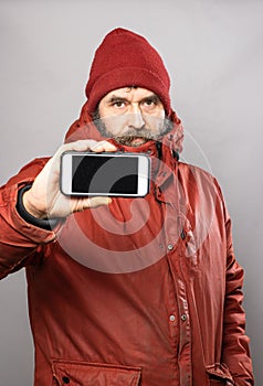 Man showing smart phone screen into camera in winter coat freezing in the cold