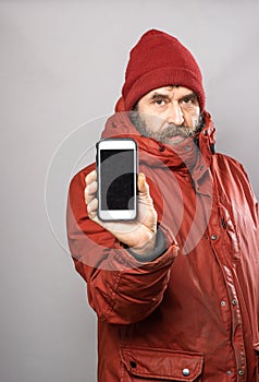 Man showing smart phone screen into camera in winter coat freezing in the cold