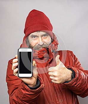 Man showing smart phone screen into camera in winter coat freezing in the cold