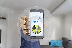 Man showing a smartphone with 5g danger sign on it