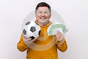 Man showing soccer ball and fun of hundred euro bills, winning lot of money betting for sport.